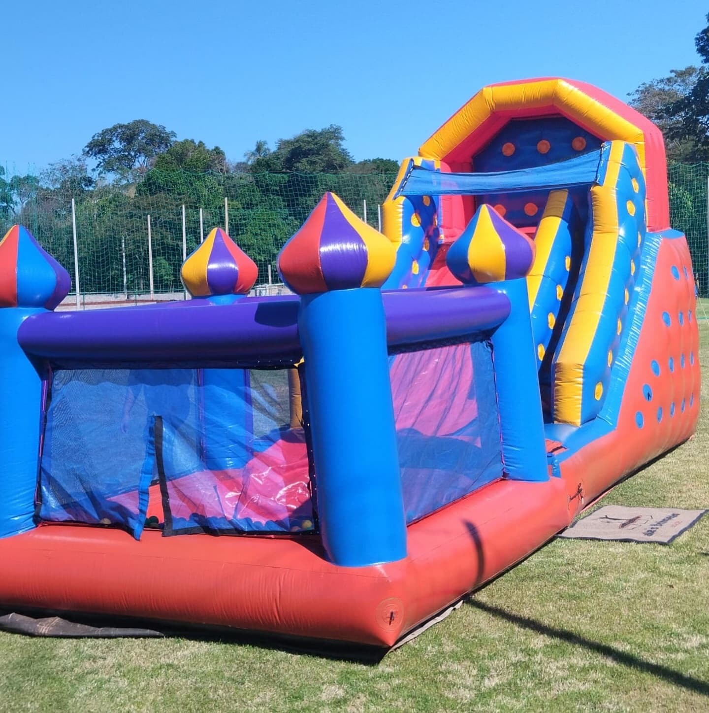 Tobogã inflável grande roxo e azul montado em um campo